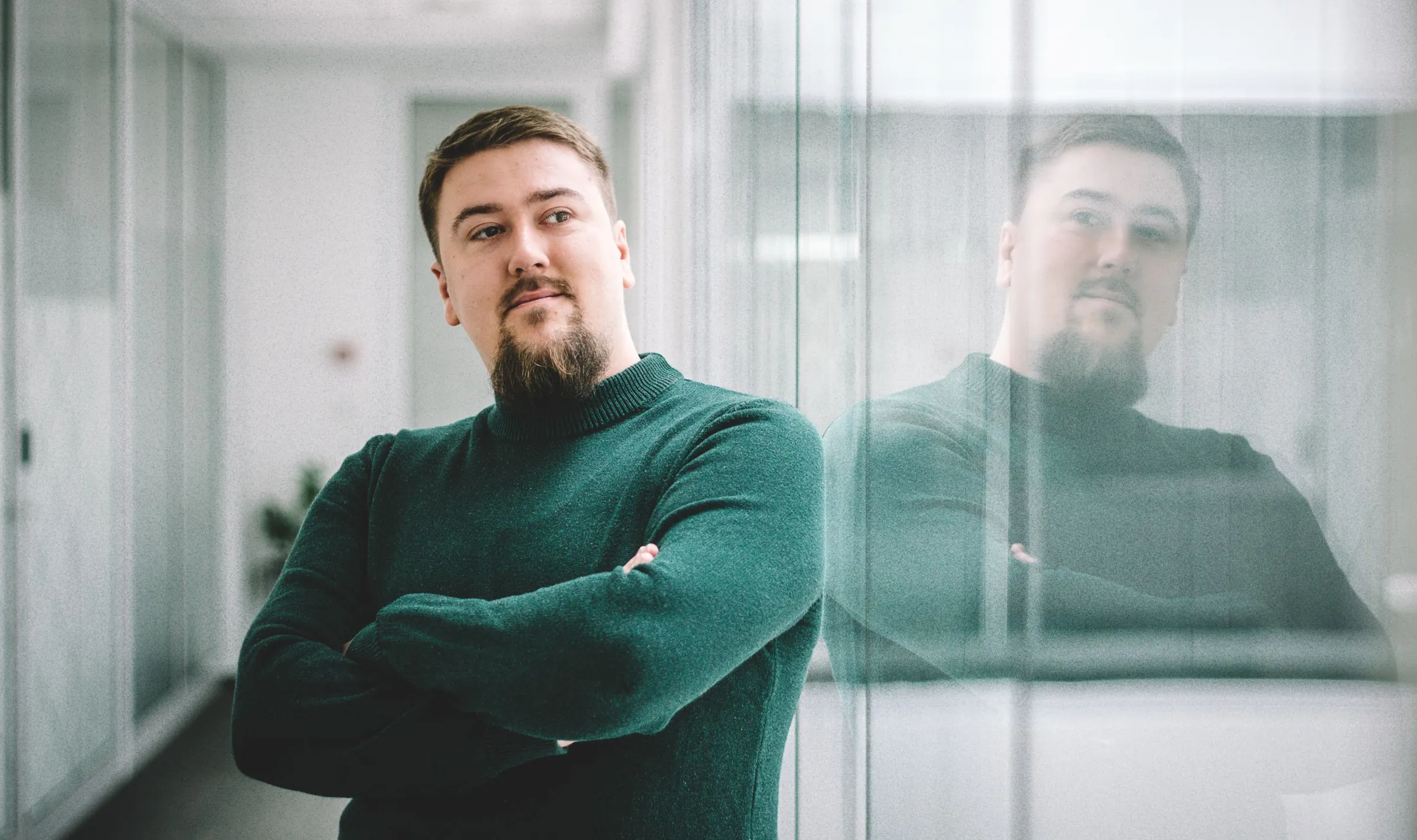 Ljubiša Kukulj leaning against a glass office wall with his arms crossed